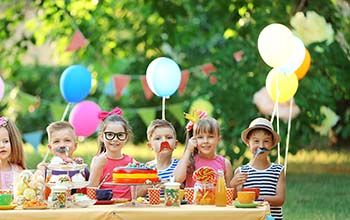 Kids celebrating birthday in park with glasses, mustache and hat props