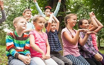 Group of positive children playing in the park sitting on the bench